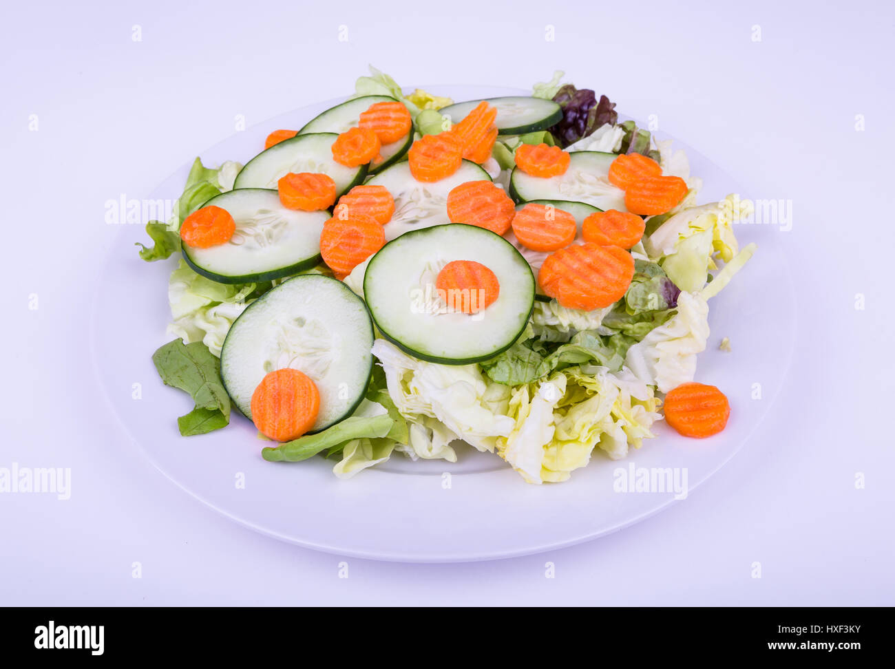 Una fresca ensalada verde de lechuga mixta, rodajas de pepino y zanahoria Foto de stock