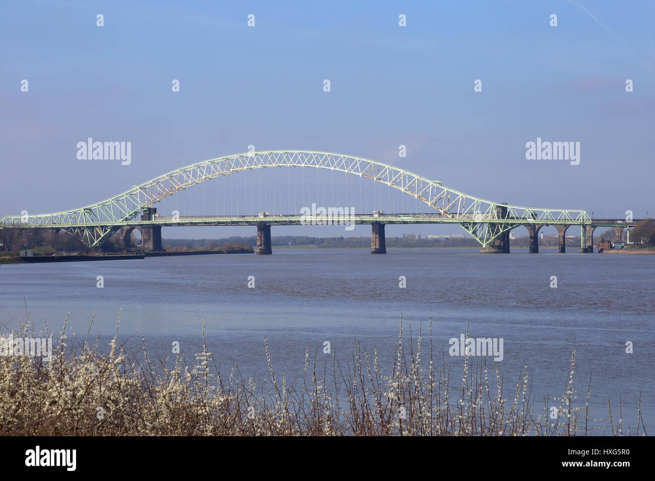 El puente Silver Jubilee en Runcorn cruzando el Manchester Ship Canal y el río Mersey. Puente ferroviario de piedra, con pilares está detrás Foto de stock
