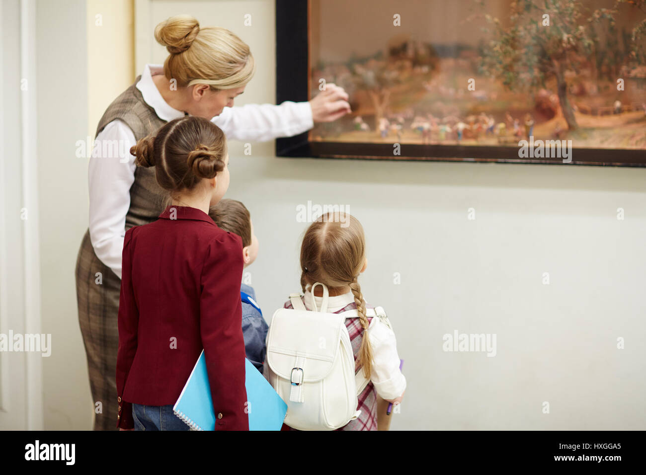 Maestro apuntando a la pintura en el museo mientras explicaba a sus alumnos los principios del arte antiguo Foto de stock