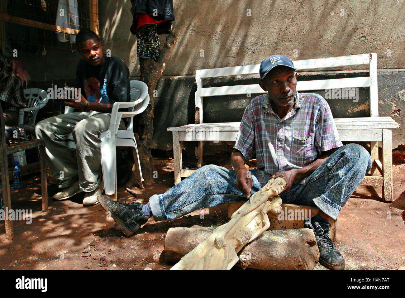 Namanga, Tanzania - Febrero 9, 2008: madera negra africana-Carver, taller de arte. Hombre africano de piel oscura, el maestro de la talla de madera, tallado woode Foto de stock