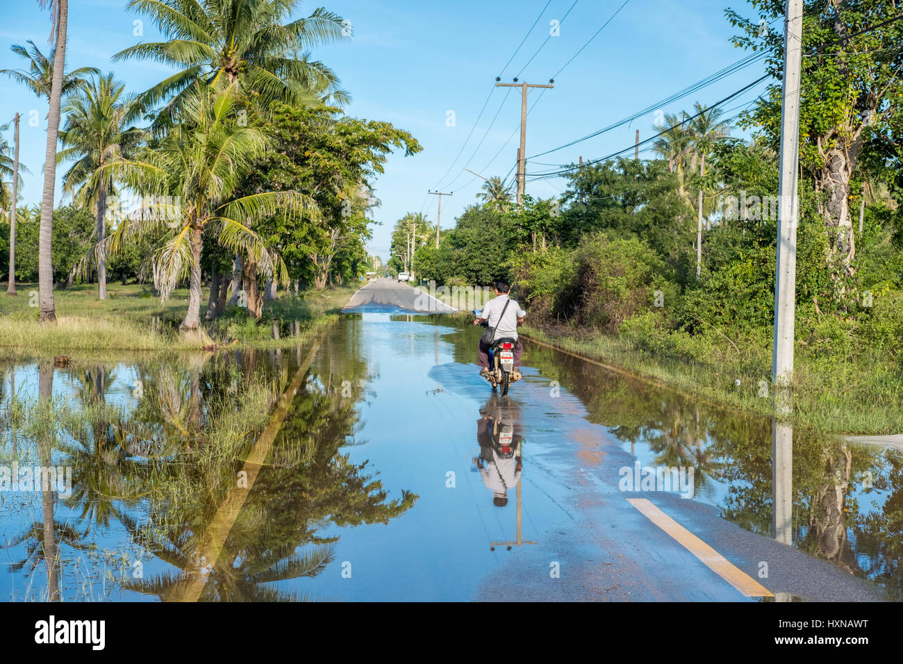 Motorbiker conducir al sur de Hua Hin después de fuertes lluvias. La temporada húmeda en Tailandia se retrasó en 2016 con lluvias torrenciales que continúan en enero de 2017. Foto de stock