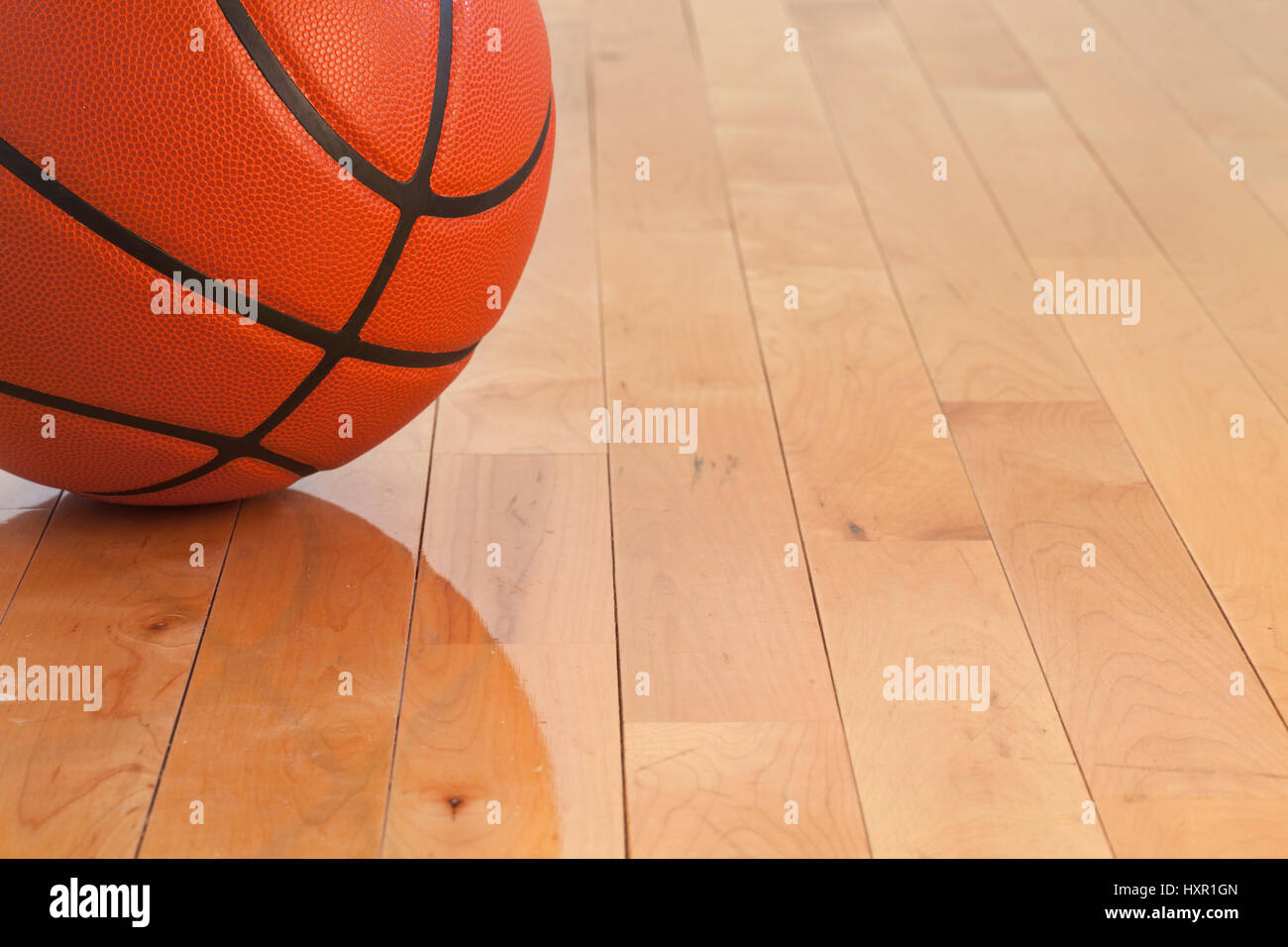 Ángulo de visión baja de un balón de baloncesto en un gimnasio de piso de madera Foto de stock