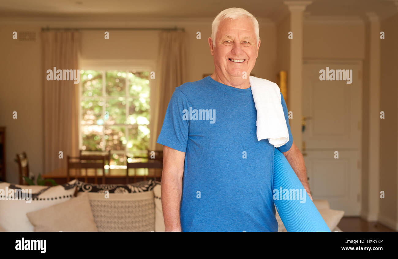 Senior activo hombre permanente en el hogar preparado para hacer yoga Foto de stock