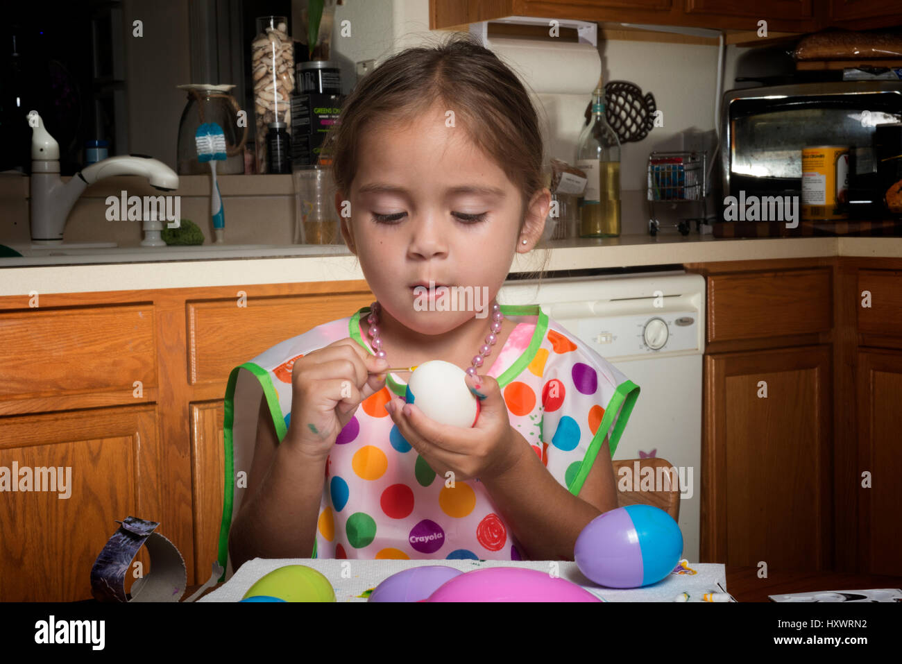 Niña colorear los huevos de Pascua en la mesa Foto de stock