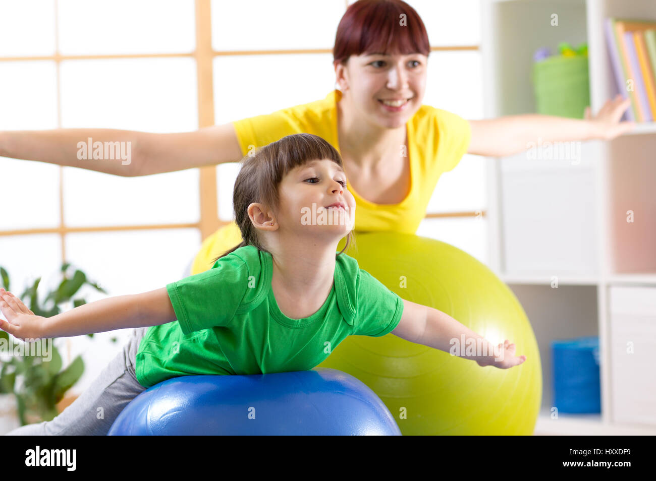 Madre haciendo gimnasia con la hija de kid en Pelota Fitness Foto de stock