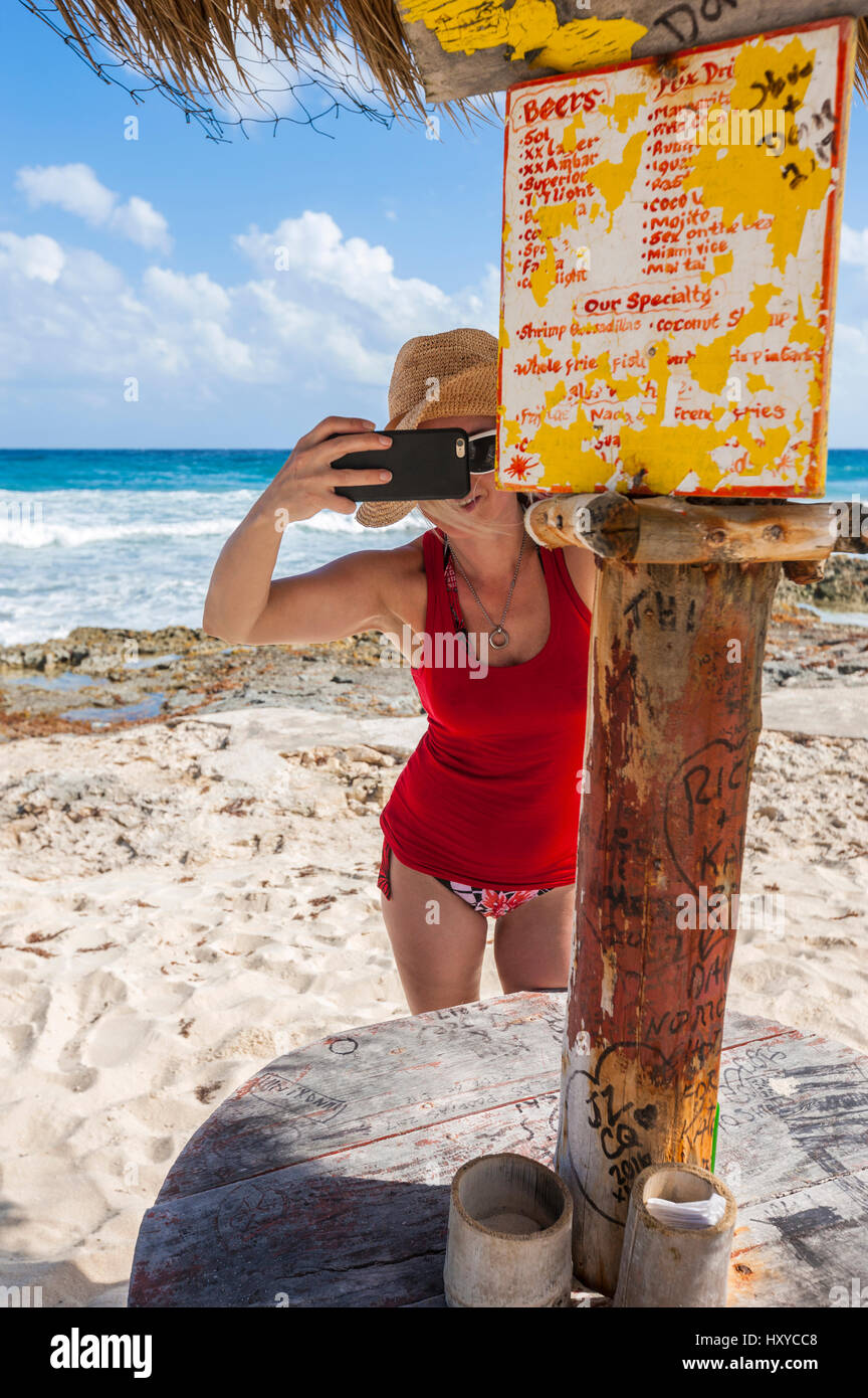 Mujer joven tomando la foto con el smartphone en el bar de la playa Foto de stock