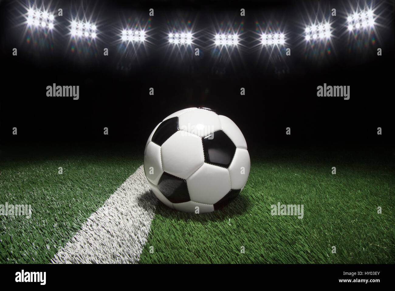 Balón de fútbol tradicional en el campo de hierba con raya bajo las luces por la noche Foto de stock