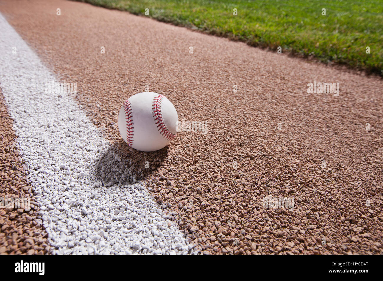 Una pelota de béisbol se asienta sobre una base senda cerca de la banda bajo las luces por la noche Foto de stock