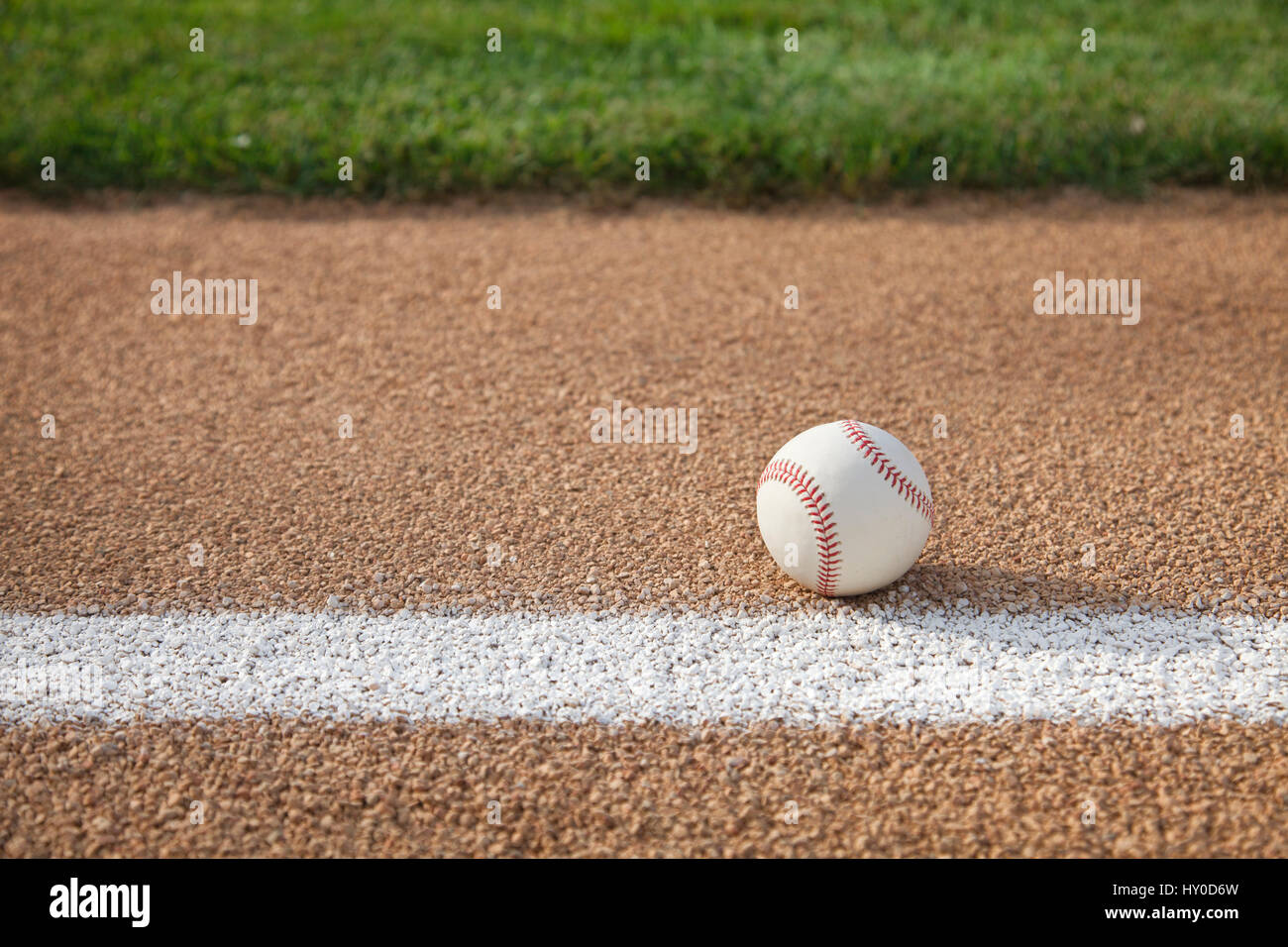 Una pelota de béisbol se asienta en una ruta de acceso base con hierba infield Foto de stock