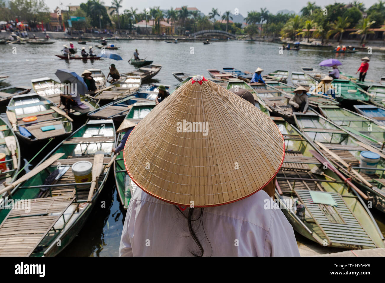Mujer Vietnamita no identificado mirando por encima de sus barcos vistiendo un sombrero de paja tradicional vietnamita en Ninh Binh, Tam Coc wharf. Foto de stock