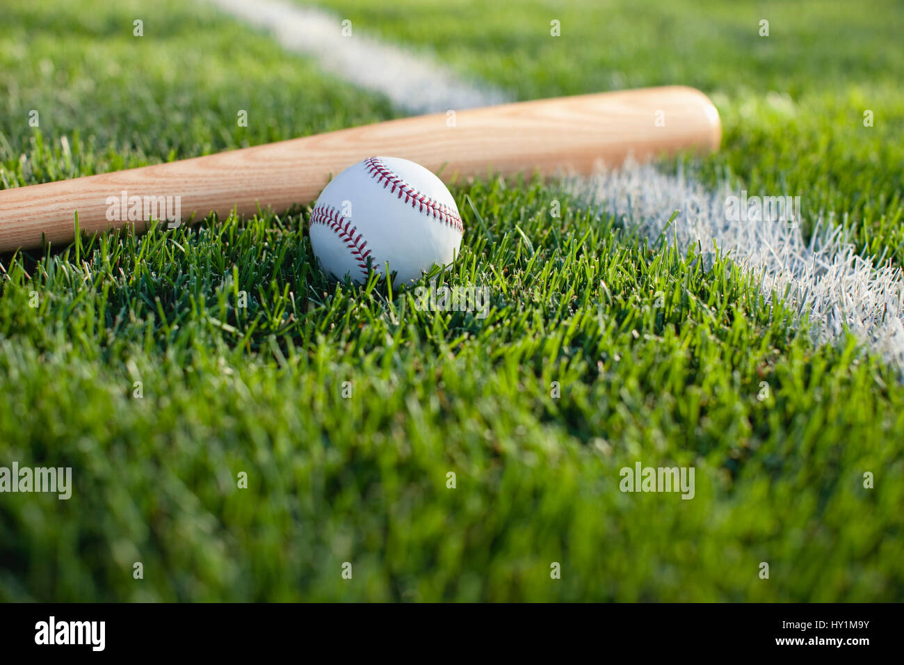 Un enfoque selectivo vista de un bate y una pelota de béisbol en la hierba cerca de una franja de campo Foto de stock