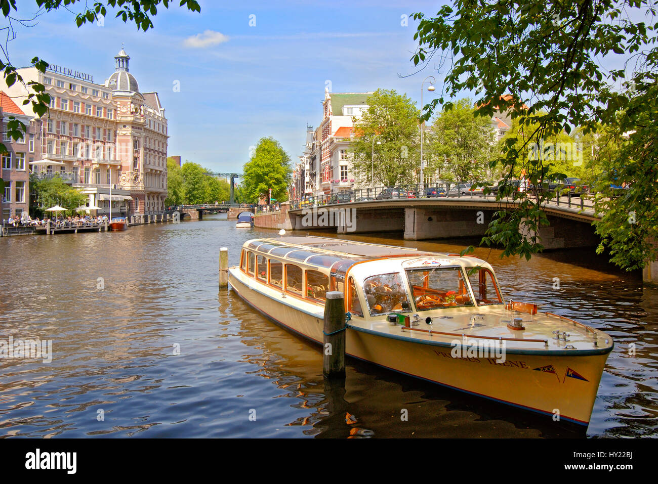 Imagen de un típico barco turístico conduciendo en un canal de agua en el interior de la ciudad de Amsterdam, Holanda. Foto de stock