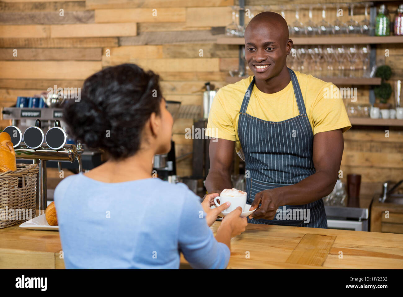 Macho feliz barista sirve café al cliente en la cafetería. Foto de stock