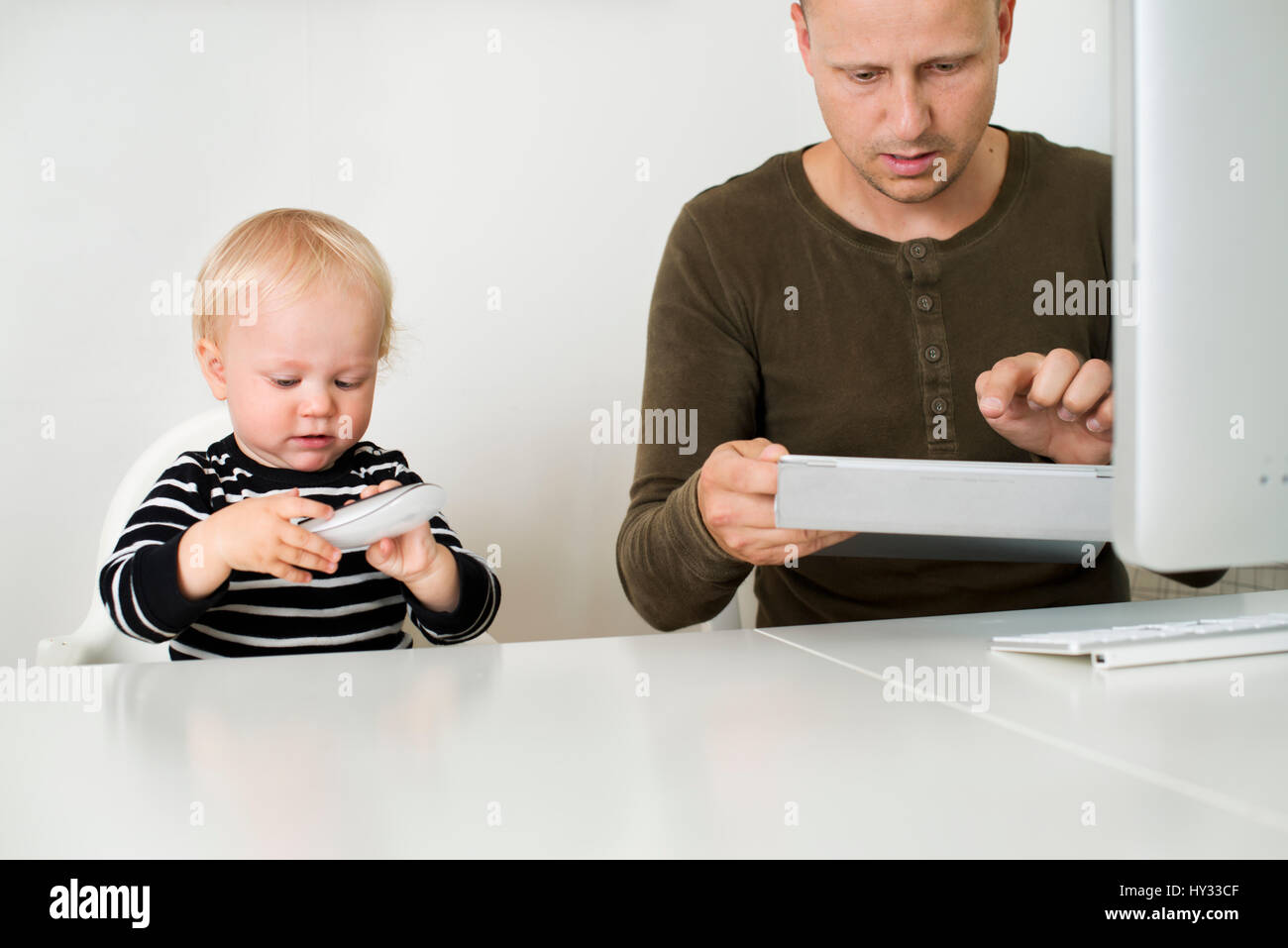 Suecia, permanecer en casa, papá con tablet, hijo (12-17 meses) jugando con el ratón del ordenador Foto de stock