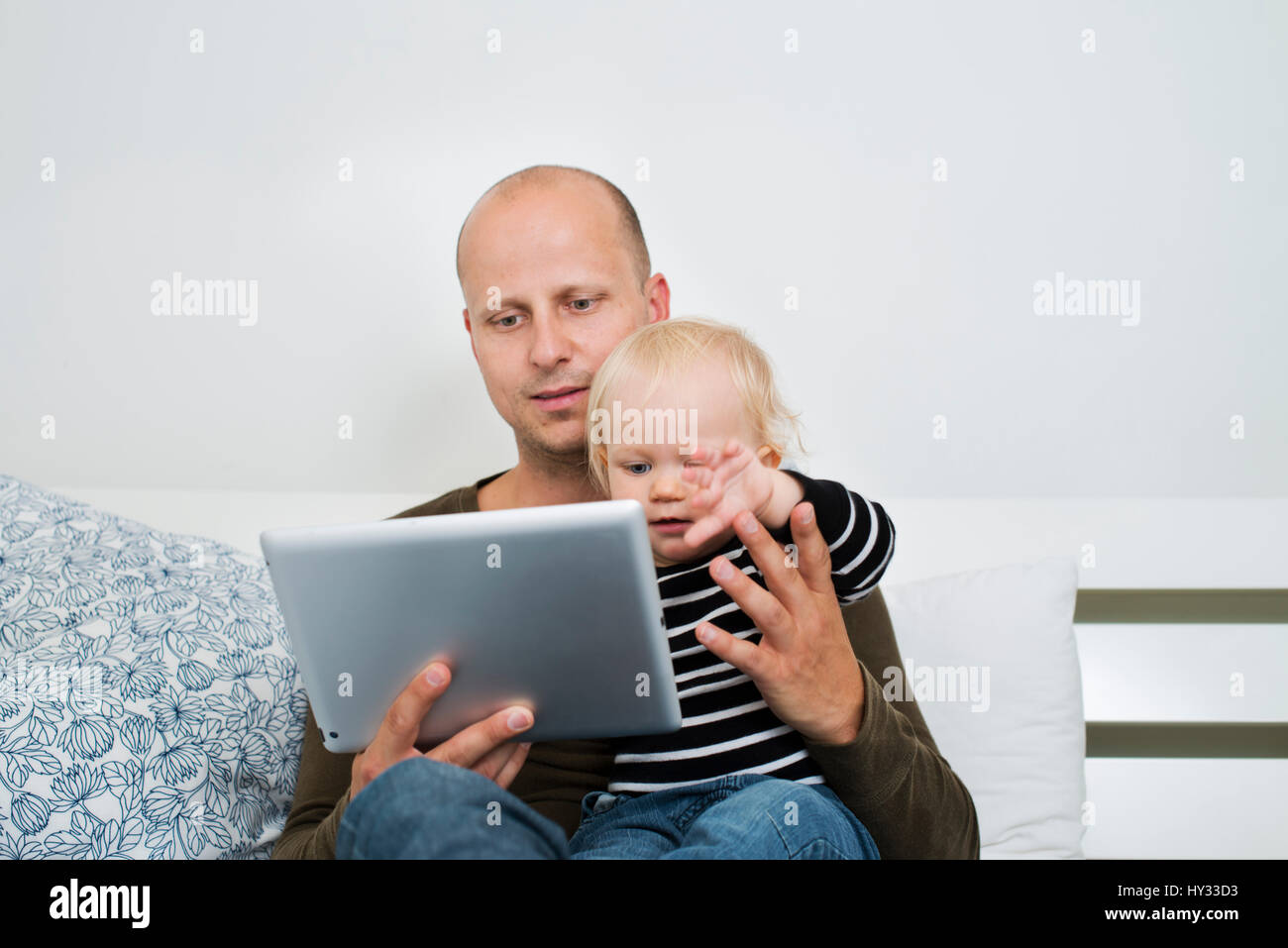 Suecia, permanecer en casa, papá con tablet sujetando hijo (12-17 meses) Foto de stock