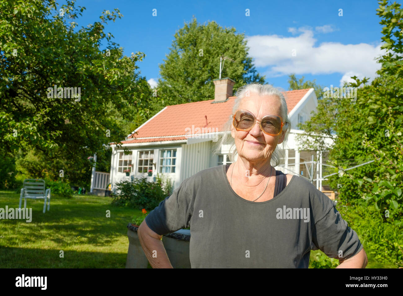Suecia, Ostergotland, Hallestad, Senior mujer en gafas de sol en el frente de su casa Foto de stock