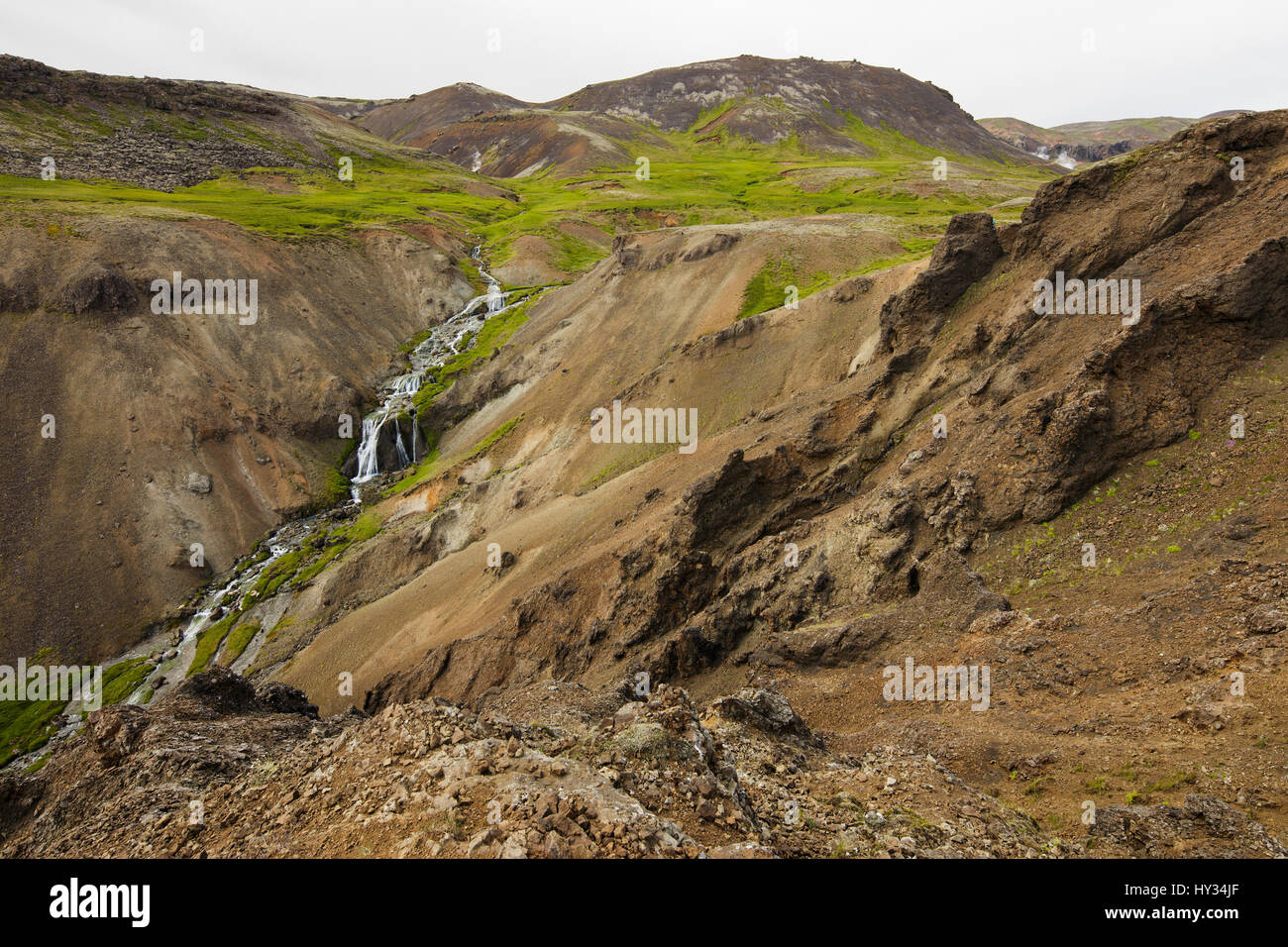 Islandia, Sudurland, Hveragerdi, Reykjadalur, Arroyo y cascadas en el valle de rocas Foto de stock