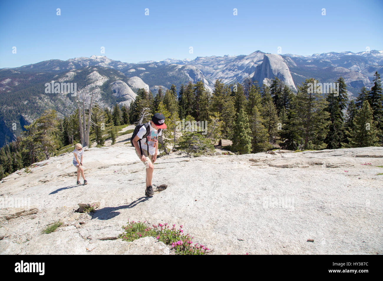 California, Estados Unidos, Yosemite, niña y niño (12-13) (14-15) caminando por la alta montaña con vista en Sentinel Dome y cataratas de Yosemite Foto de stock