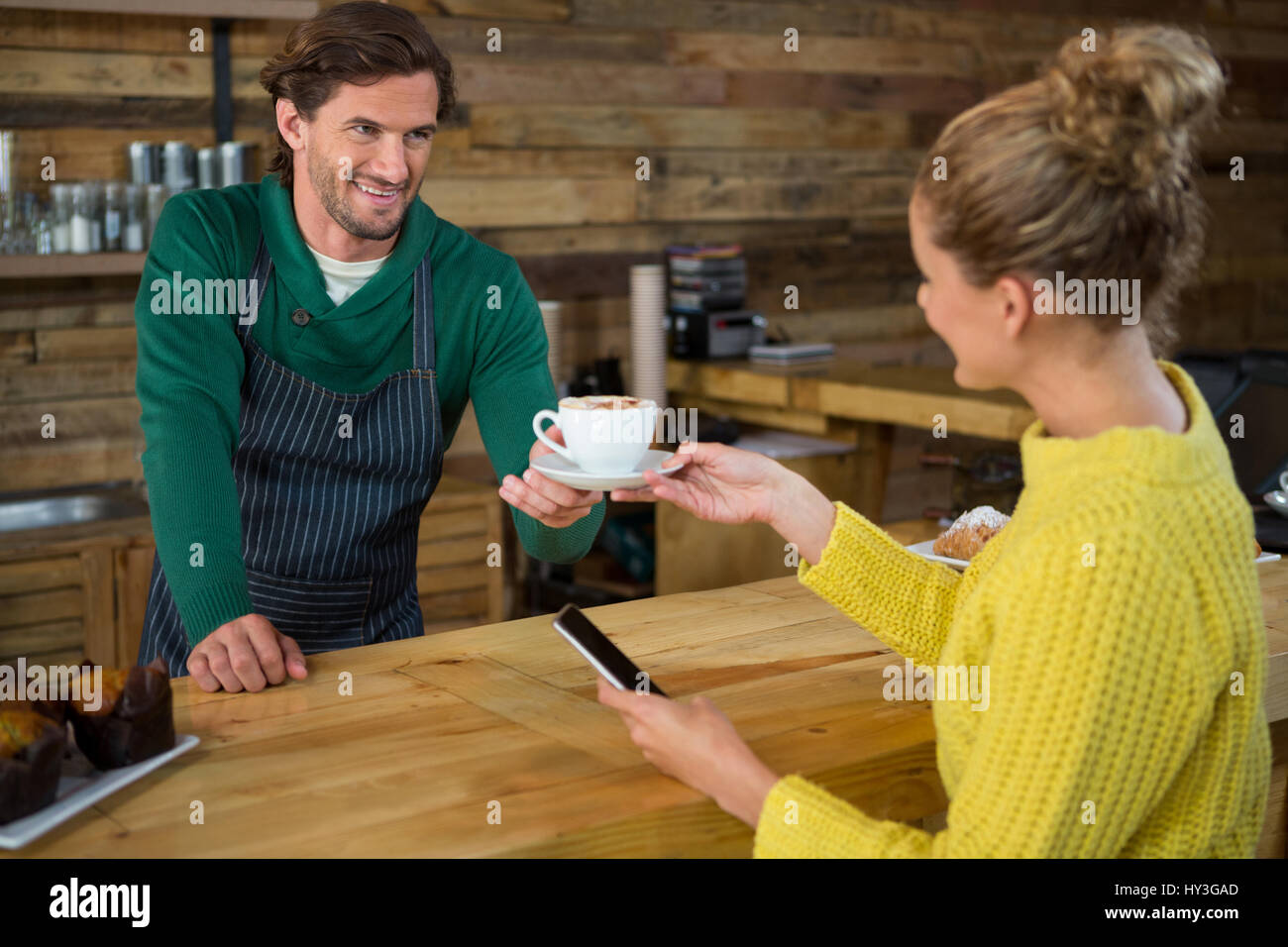 Sonriendo macho a hembra barista sirve café en la cafetería del cliente Foto de stock