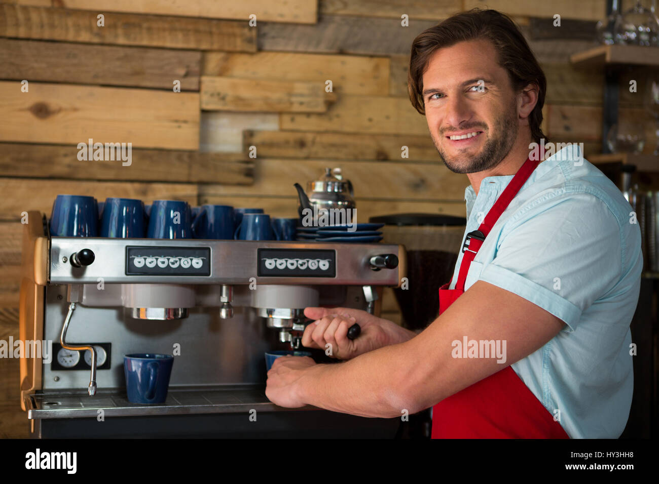 Retrato de hombres sonrientes barista preparar café con la máquina en la cafetería. Foto de stock