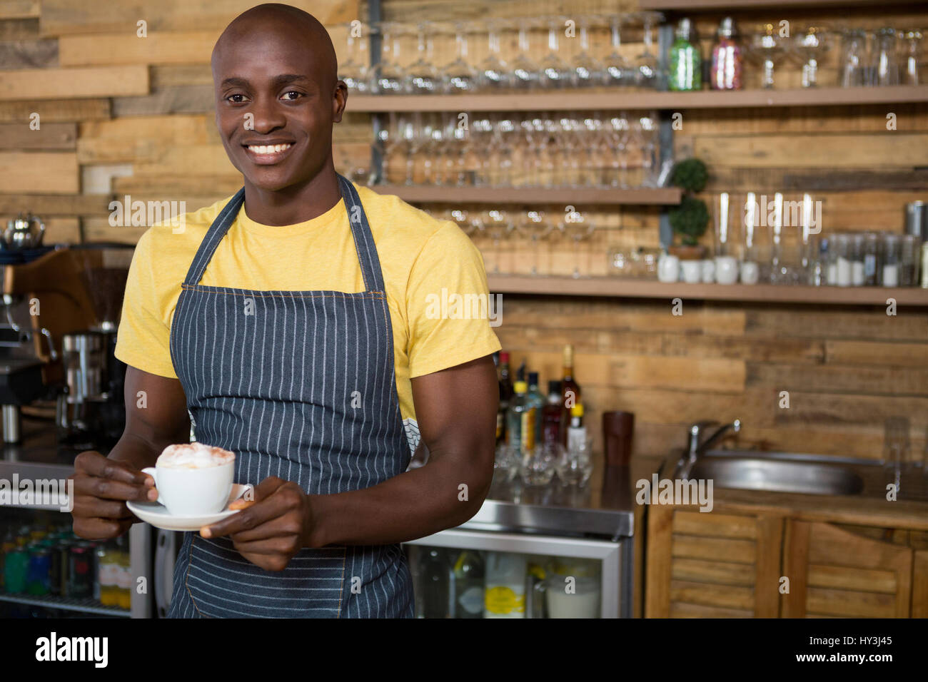 Retrato de barista macho sonriente sosteniendo la taza de café en la cafetería Foto de stock