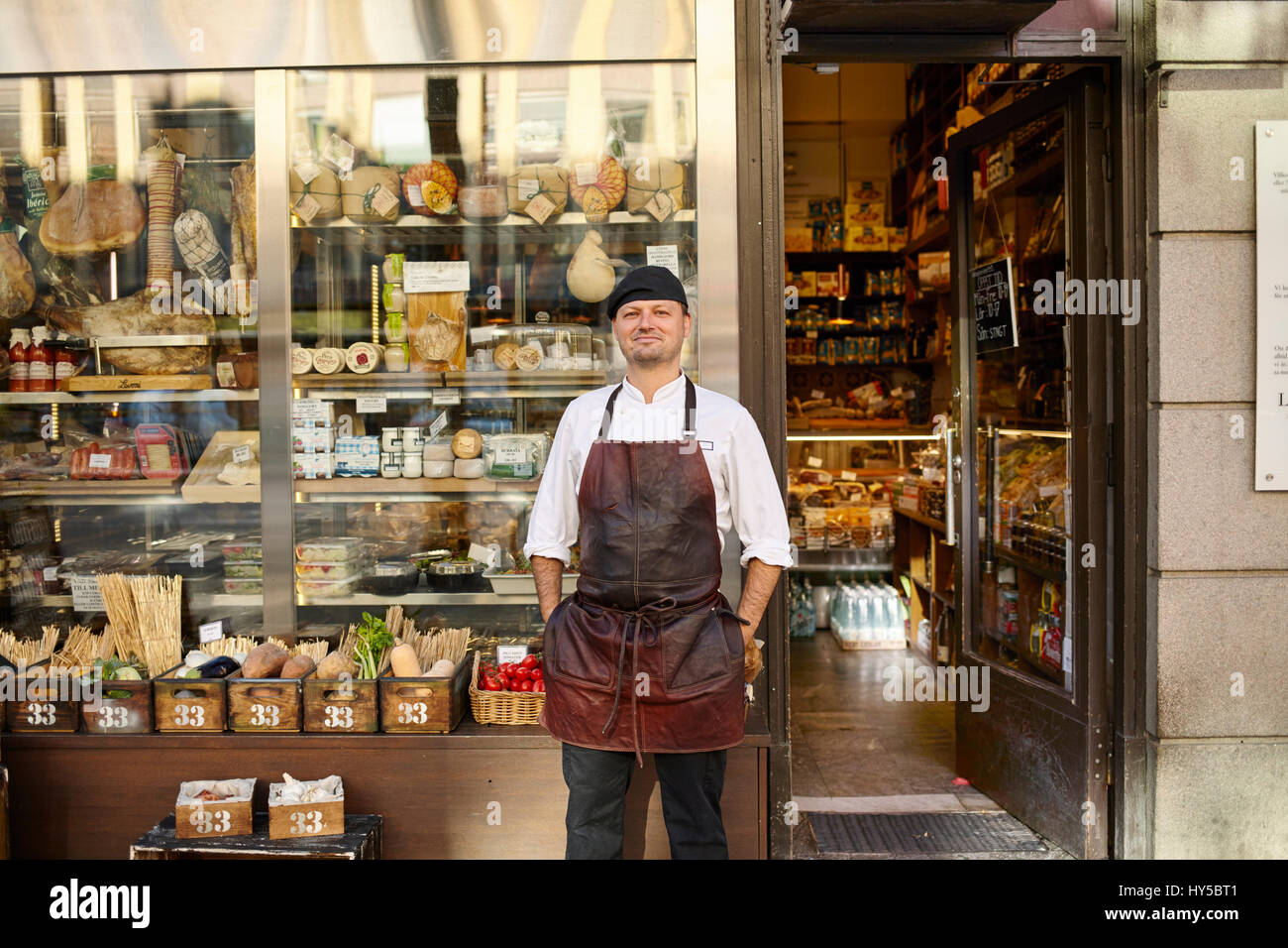 Suecia, el hombre en el delantal de pie en frente de la tienda Foto de stock
