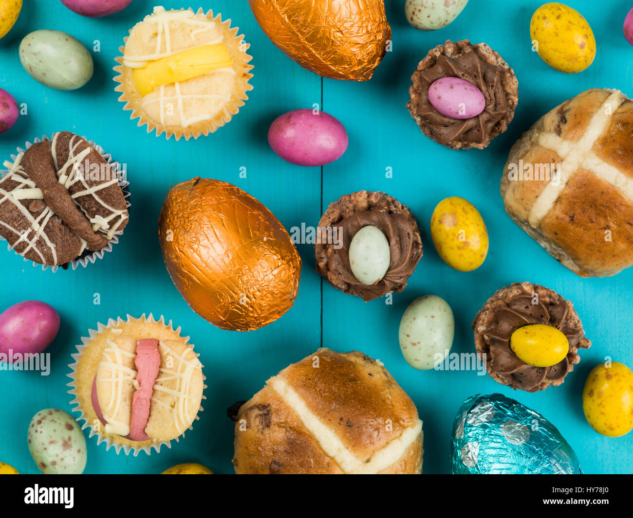 Selección de tradicionales pasteles de Pascua y huevos de pascua de chocolate mini contra un fondo azul. Foto de stock