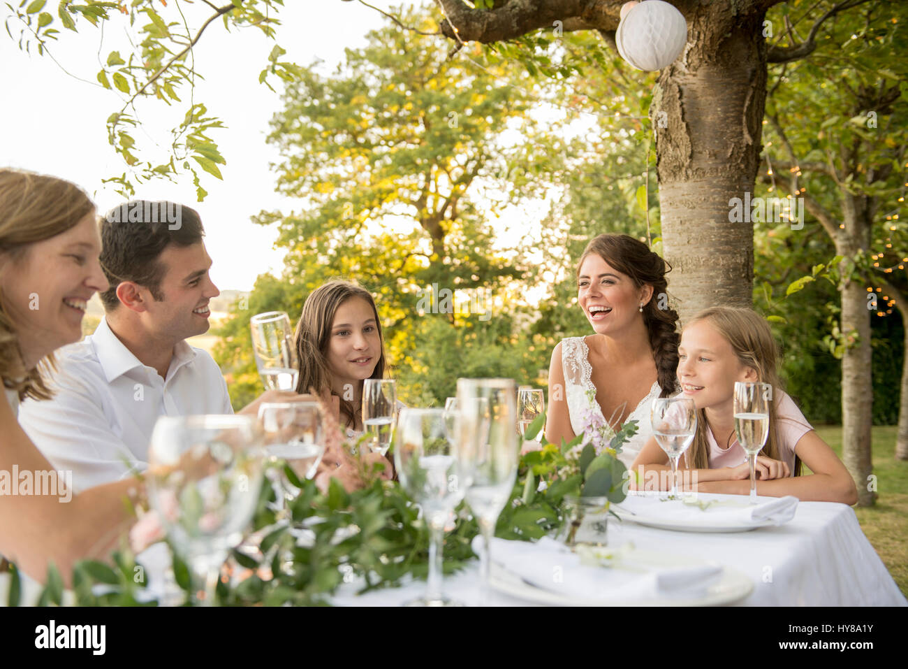 La novia y el novio sentado en la mesa con sus amigos en una boda exterior Foto de stock