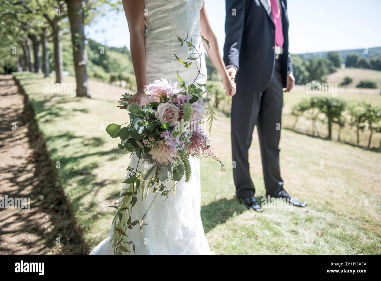 Una pareja de recién casados stand tomados de las manos en el día de su boda Foto de stock