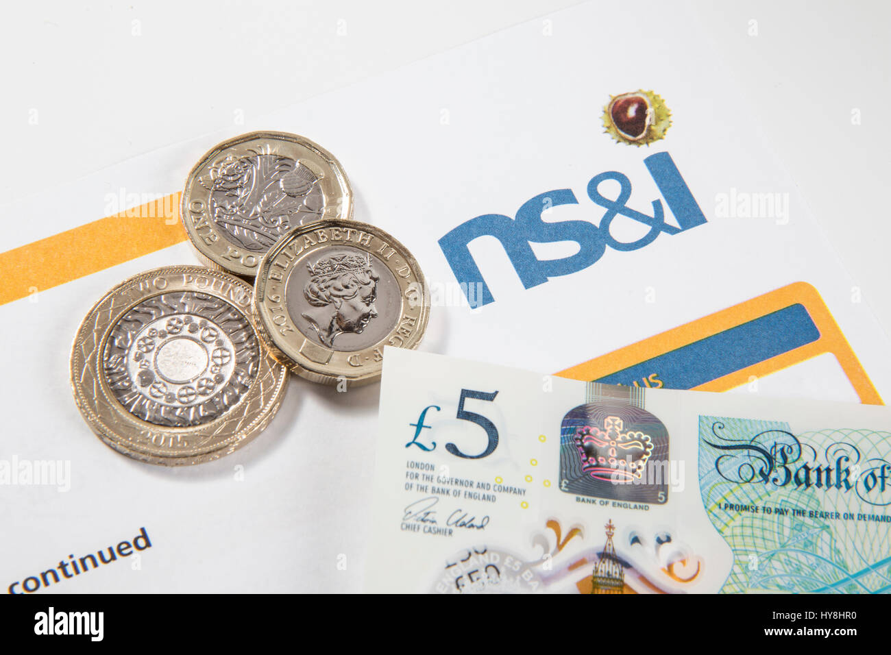 Nuevo £1 libras de monedas, £2 libras de monedas y de £5 libras notas sobre un documento bonos premium Foto de stock