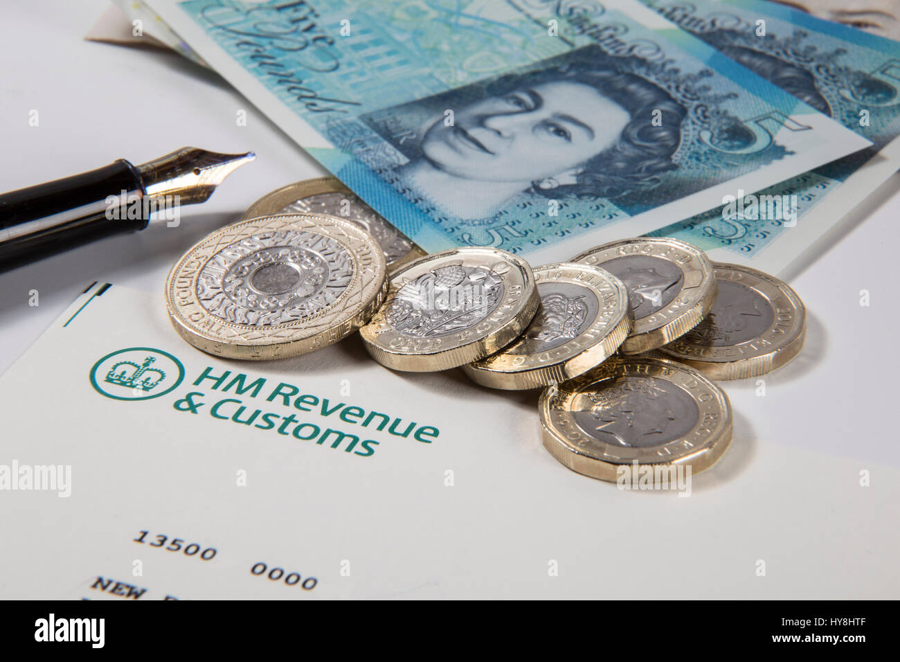 Nuevo £1 libras de monedas, £2 libras de monedas y de £5 libras notas en un HM Ingresos & documento aduanero Foto de stock