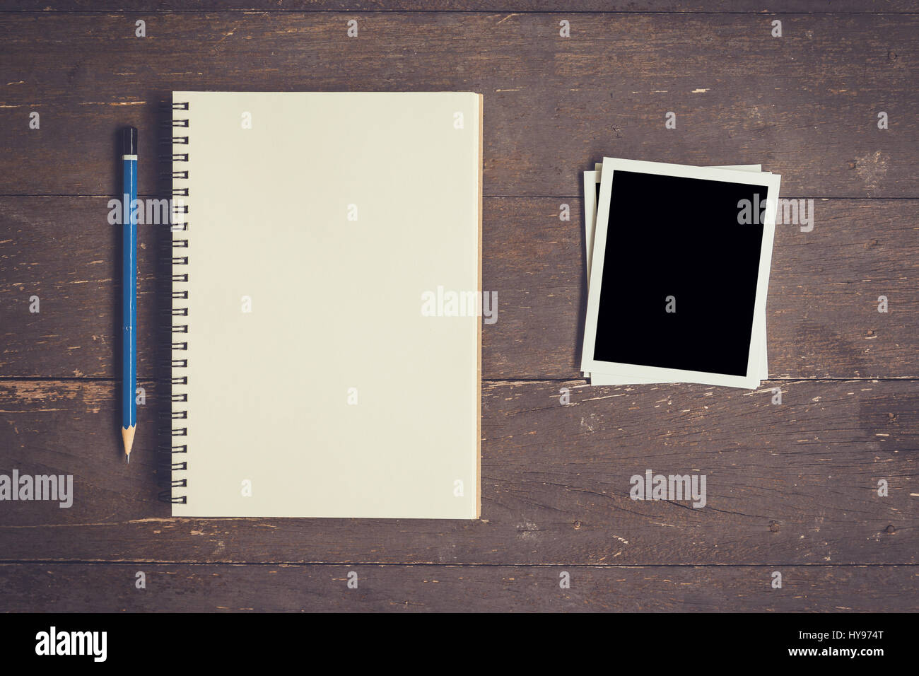 Cuaderno y lápiz con marco de foto en el fondo de la tabla de madera con espacio Foto de stock