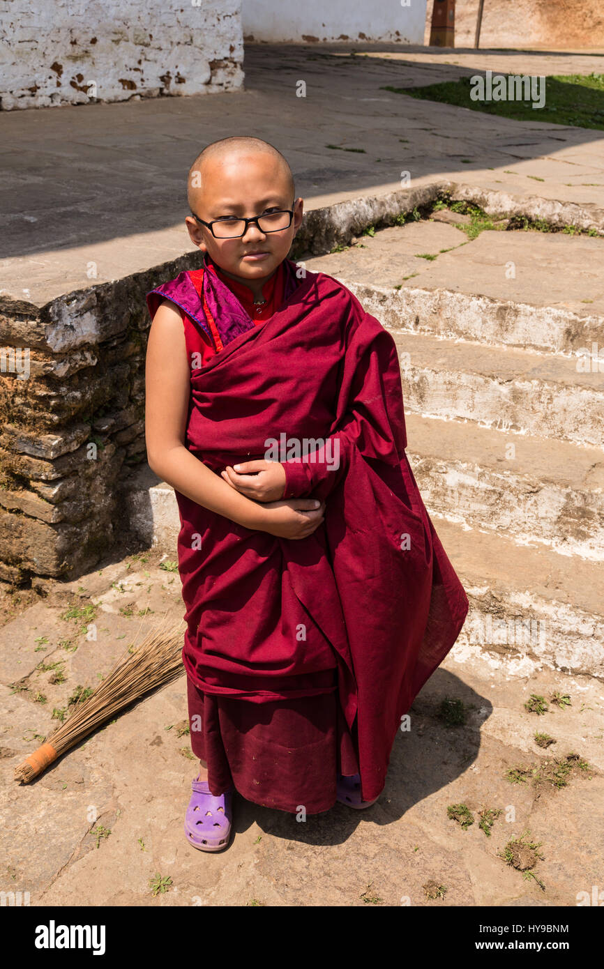 Un joven budista principiante en azul brillante y sandalias posa para una foto en el talo monasterio en Bhután Fotografía de - Alamy