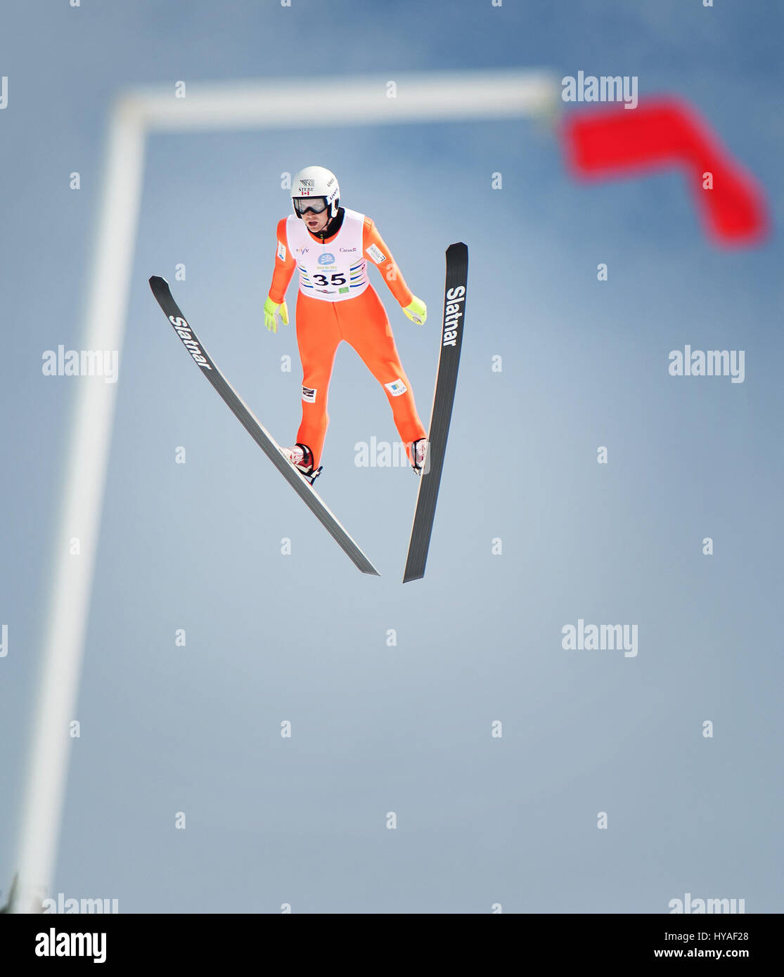 El equipo de Canadá esquí Mackenzie Boyd-Clowes puente está enmarcada por una bandera de viento mientras vuela fuera de la colina grande saltar en el Whistler Olympic Park durante el 2017 Foto de stock