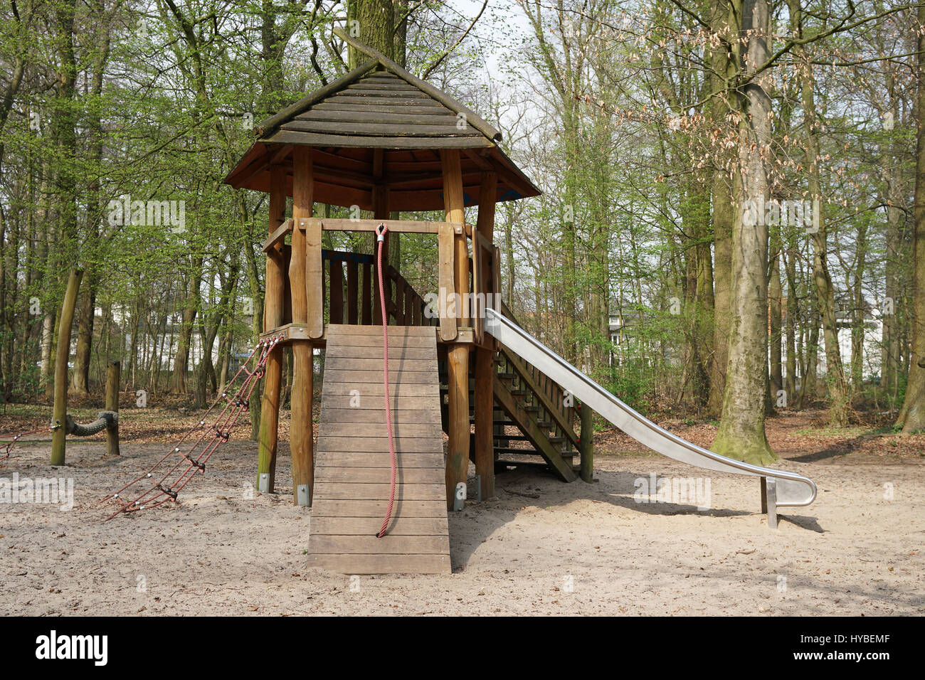 Bosque parque infantil con cabaña de madera y deslice Foto de stock
