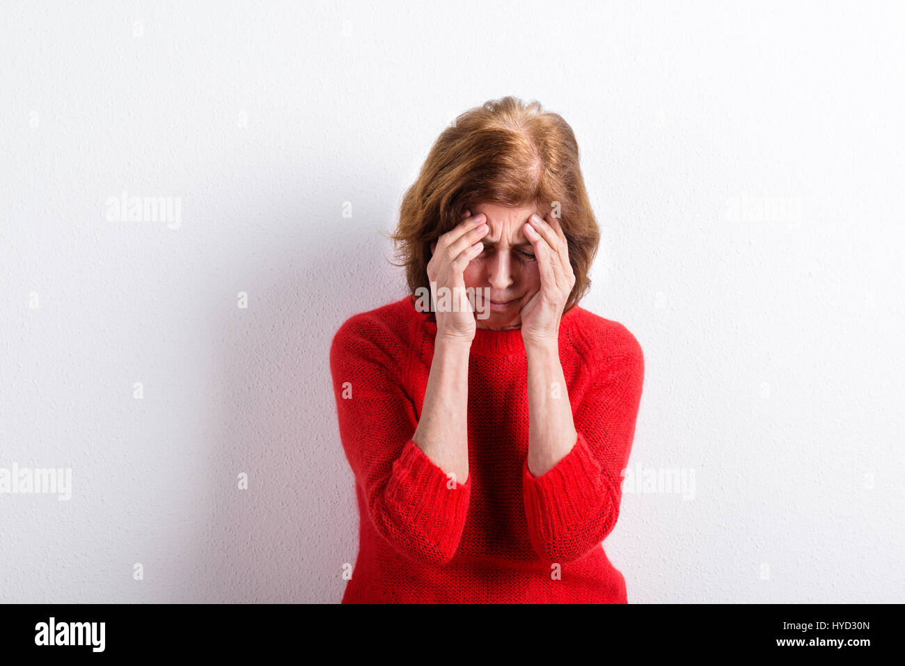 Senior mujer sosteniendo la cabeza, tener dolor de cabeza. Foto de estudio. Foto de stock