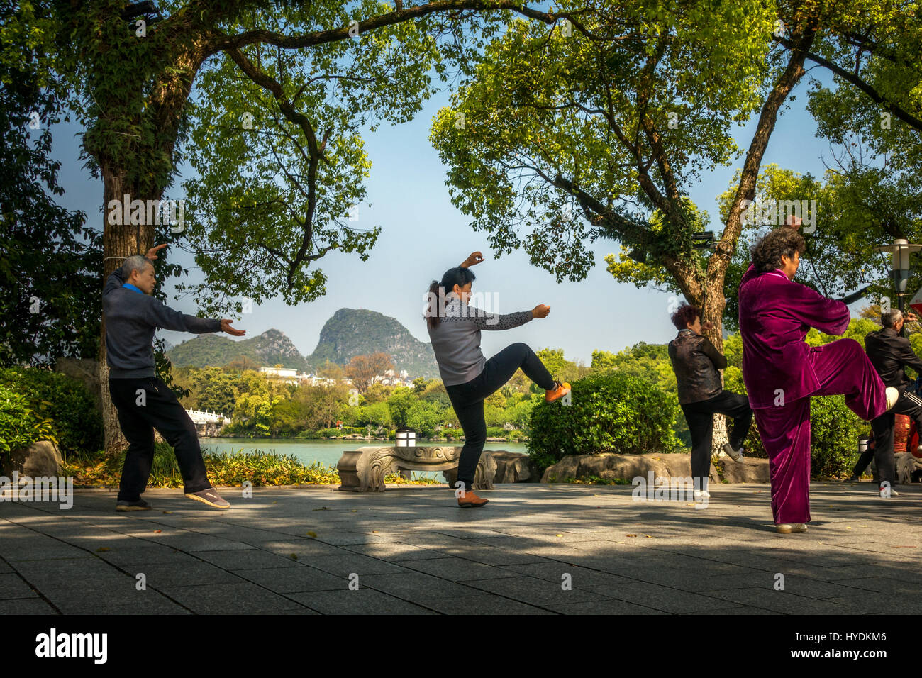 La gente disfruta de ejercicios de Tai Chi junto al agua en Guilin, China Foto de stock