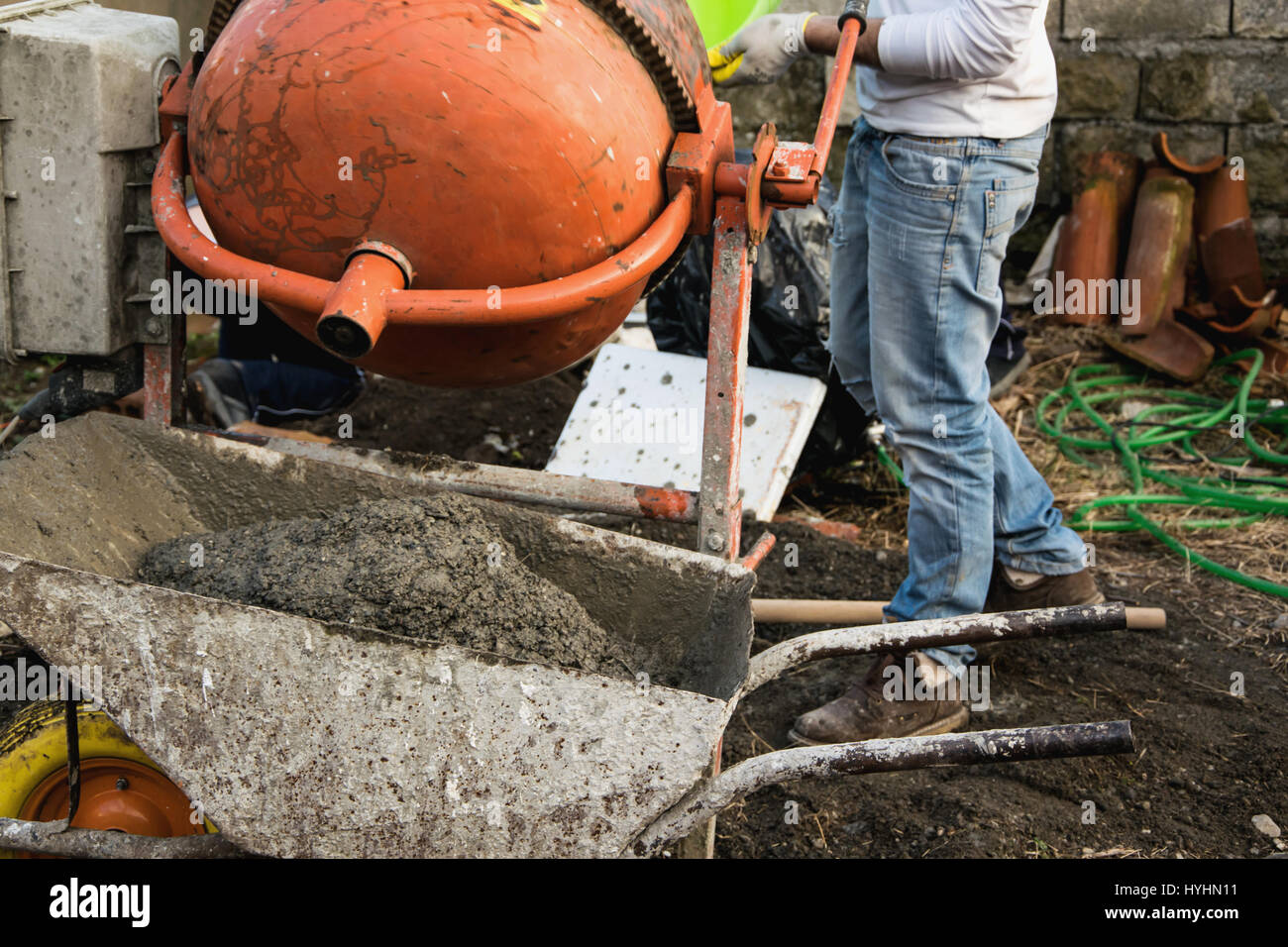 Un albañil vierte agua en el mezclador de cemento Fotografía de stock -  Alamy