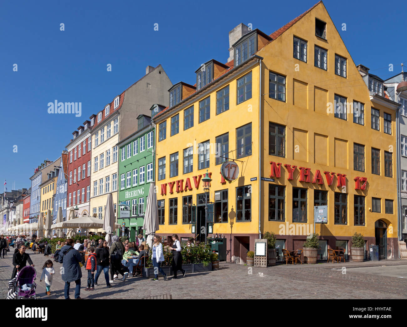 Los restaurantes frente al mar, en Nyhavn, Copenhague, Dinamarca, atraen a muchos turistas y Copenhageners en un soleado día de primavera, a principios de abril Foto de stock