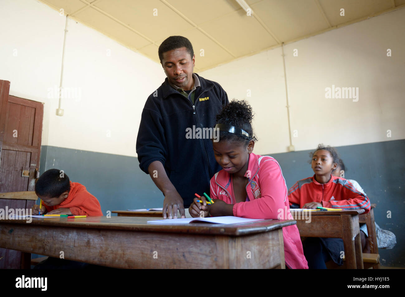 Profesor ayudando a un estudiante de sexo femenino, 15 años, escuela primaria, Fianarantsoa, Madagascar Foto de stock