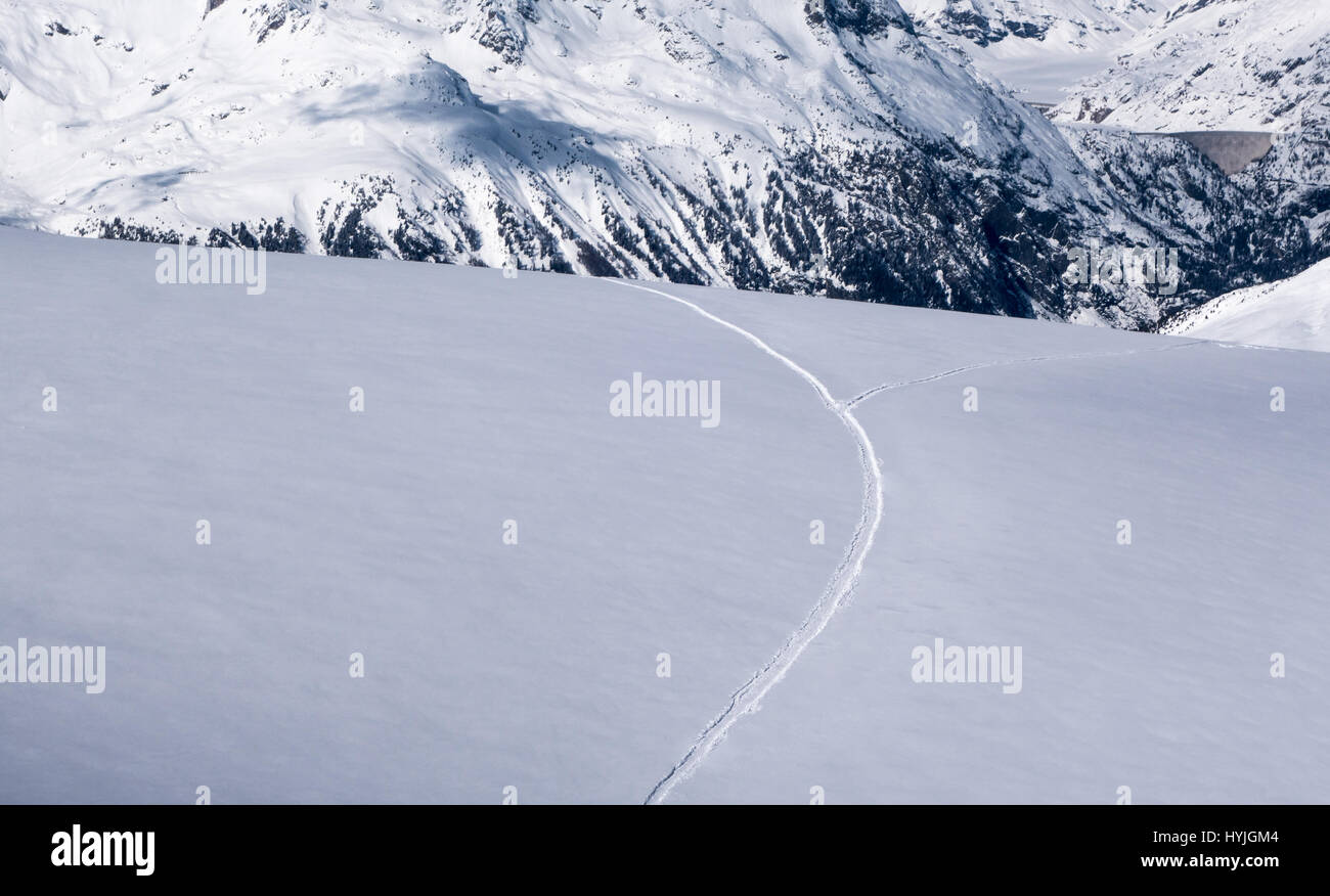 Pista de esquí de nieve untracked campo después de nevadas recientes dividiéndose en dos caminos diferentes maneras por la ladera de los Alpes en invierno Foto de stock