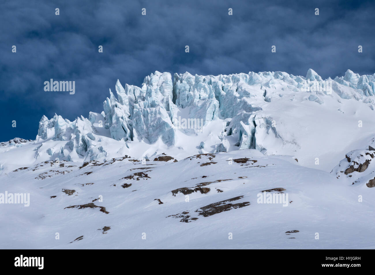 Detalle del Glaciar du Tour con resquicios bloques de hielo grietas que sobresalen del paisaje de invierno iluminado por la luz solar a través de las nubes en los Alpes hacia atrás Foto de stock