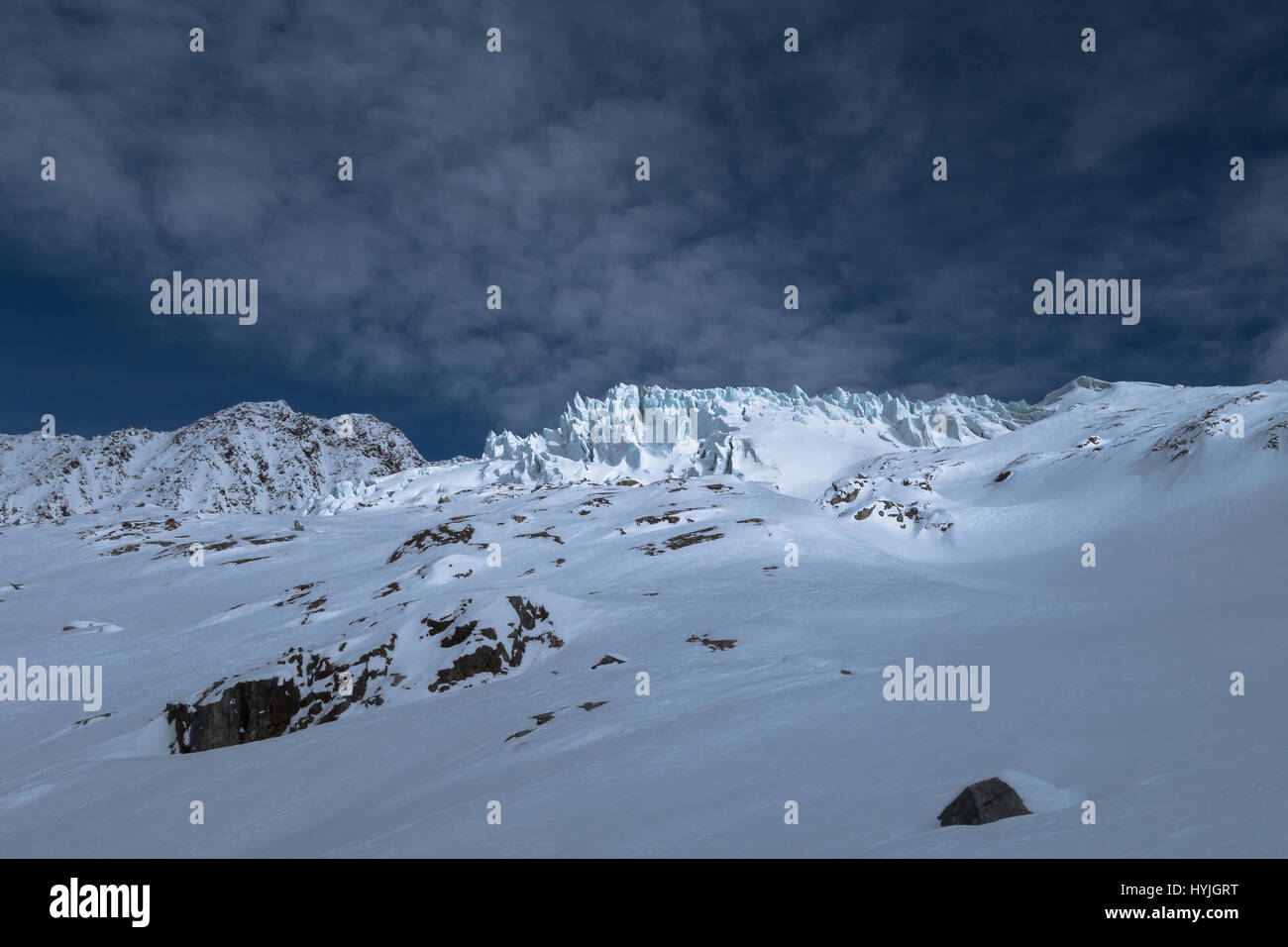 Parte del Glaciar du Tour con resquicios bloques de hielo grietas iluminado por la luz solar a través de las nubes en el horizonte de un vasto paisaje de invierno en los Alpes Foto de stock
