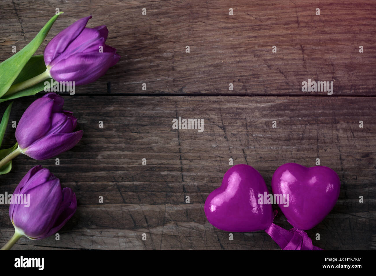 Los tulipanes y el corazón púrpura sobre fondo de madera con espacio de copia Foto de stock