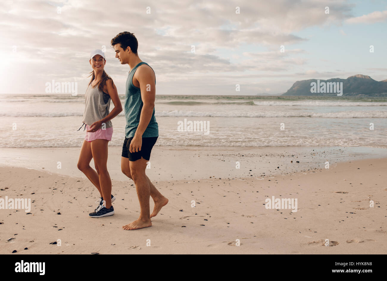 Disparó al aire libre de la joven pareja caminando por la orilla. Joven Hombre y Mujer paseando por la playa por la mañana. Foto de stock