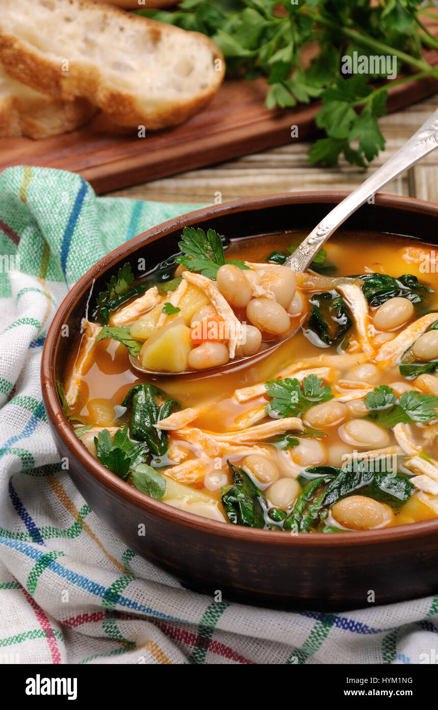 Sopa de pollo con judías blancas, las espinacas y el tomate Fotografía