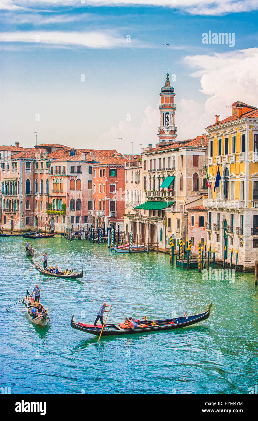 Vista vertical tradicional de las Góndolas en el Canal Grande, con el campanario de la iglesia de Santi Apostoli histórico en el fondo en un día soleado en Venecia. Foto de stock