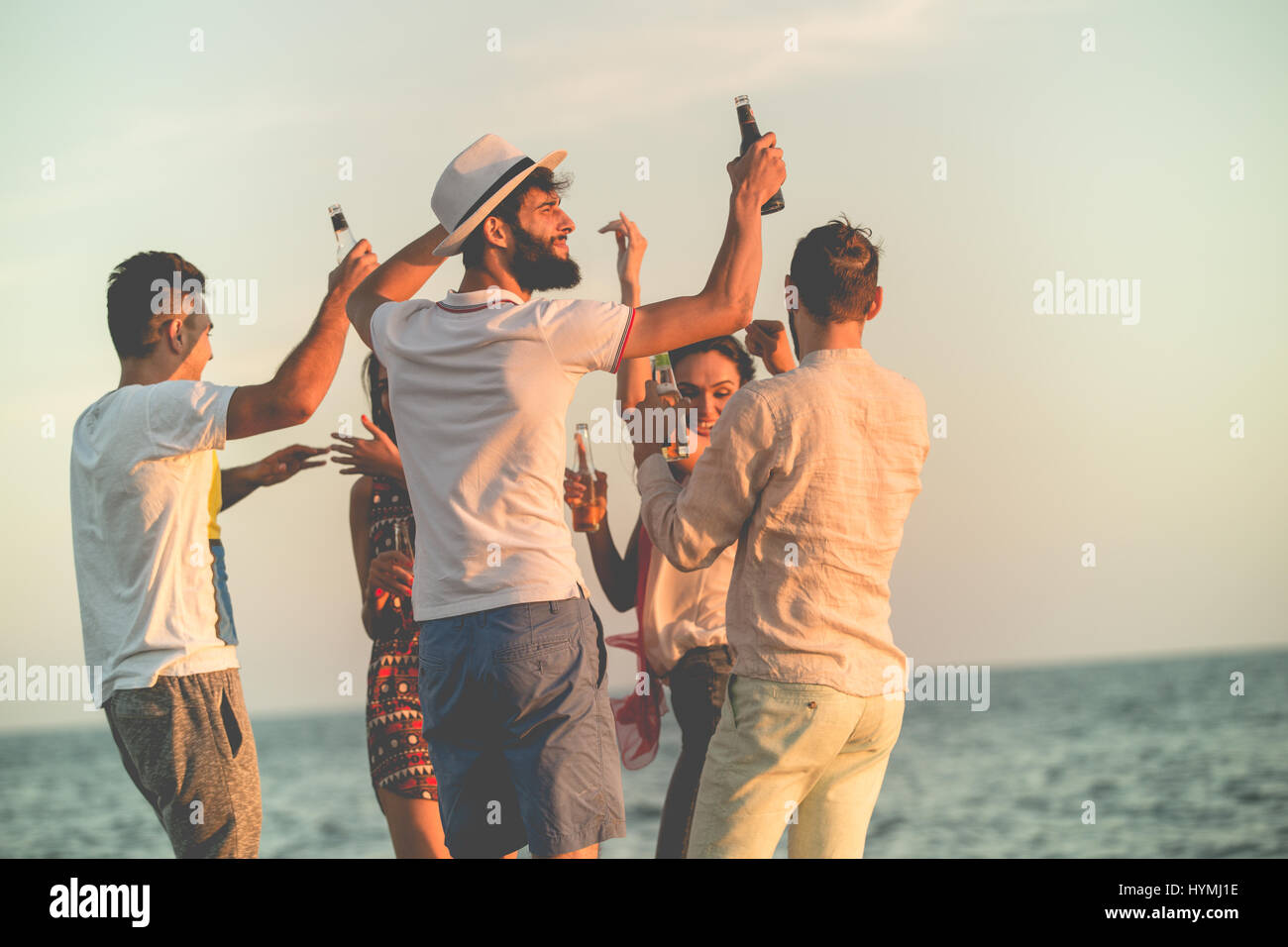 Grupo de jóvenes felices bailando en la playa en el hermoso atardecer de verano Foto de stock