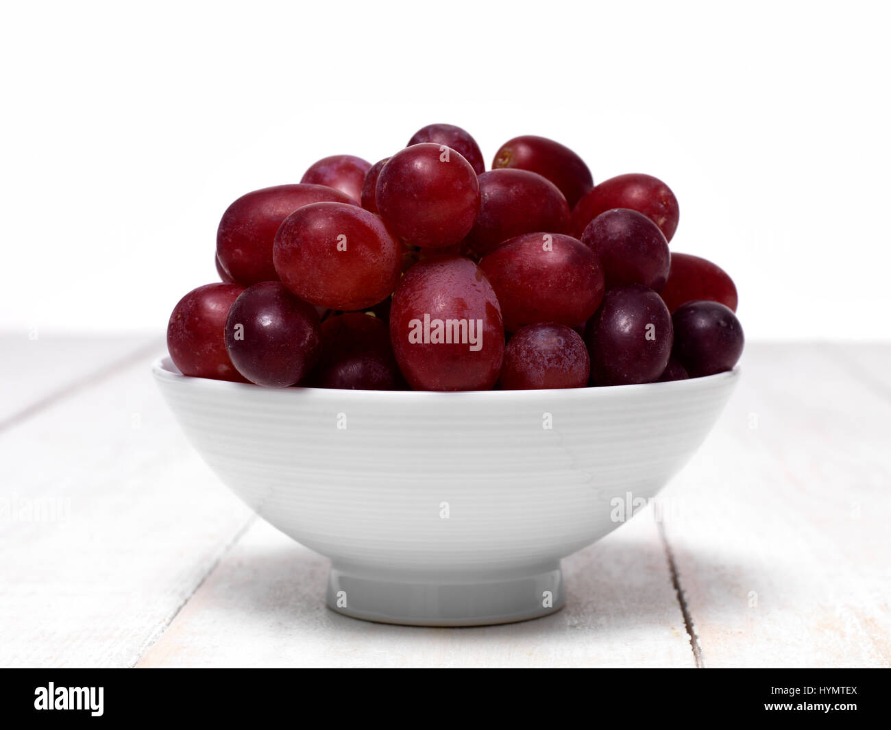 Las uvas rojas en un tazón pequeño Foto de stock
