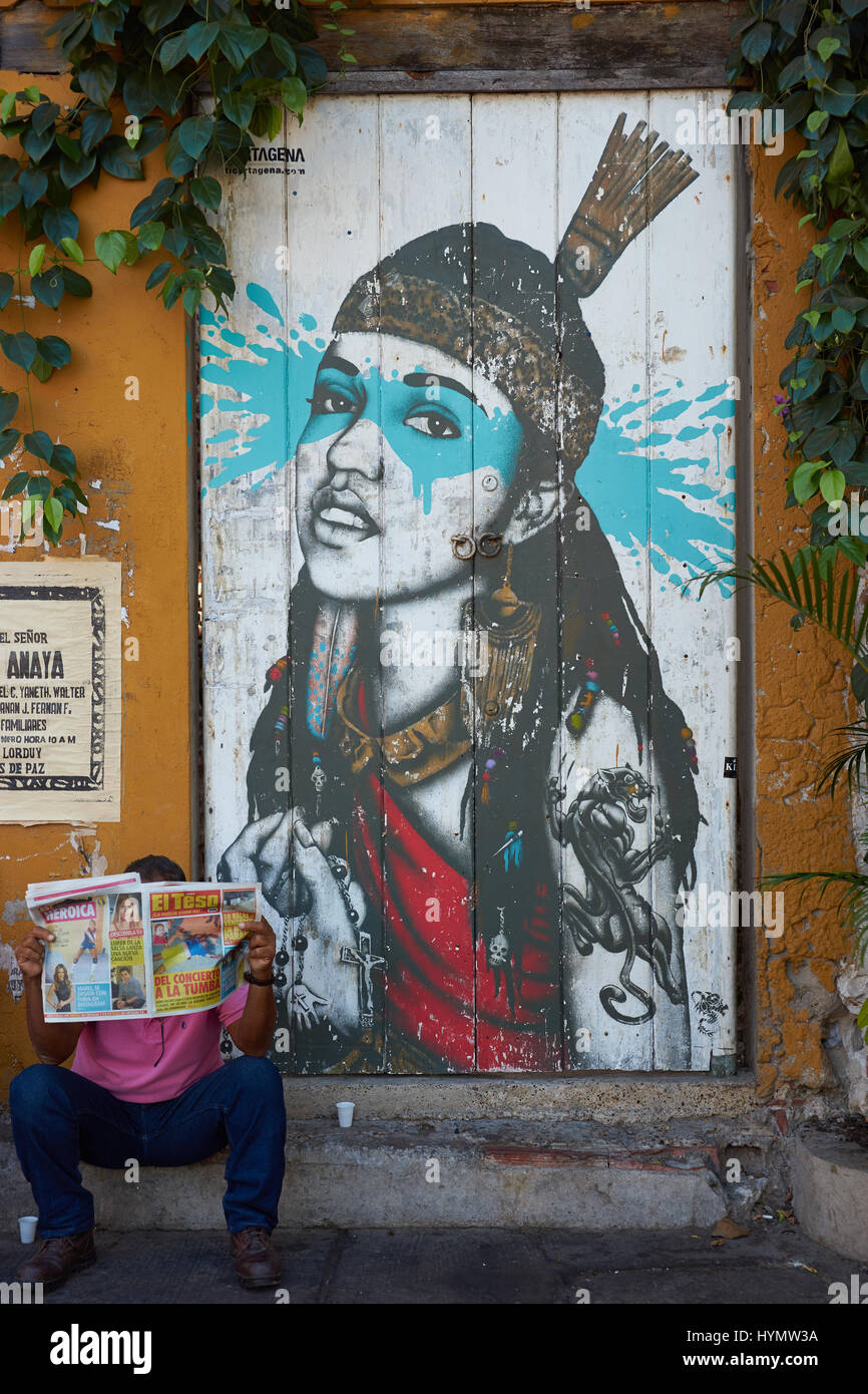 Hombre leyendo un periódico delante de un mural colorido decorar una puerta  de madera en la zona Getsemini histórico de la ciudad de Cartagena en  Colombia Fotografía de stock - Alamy